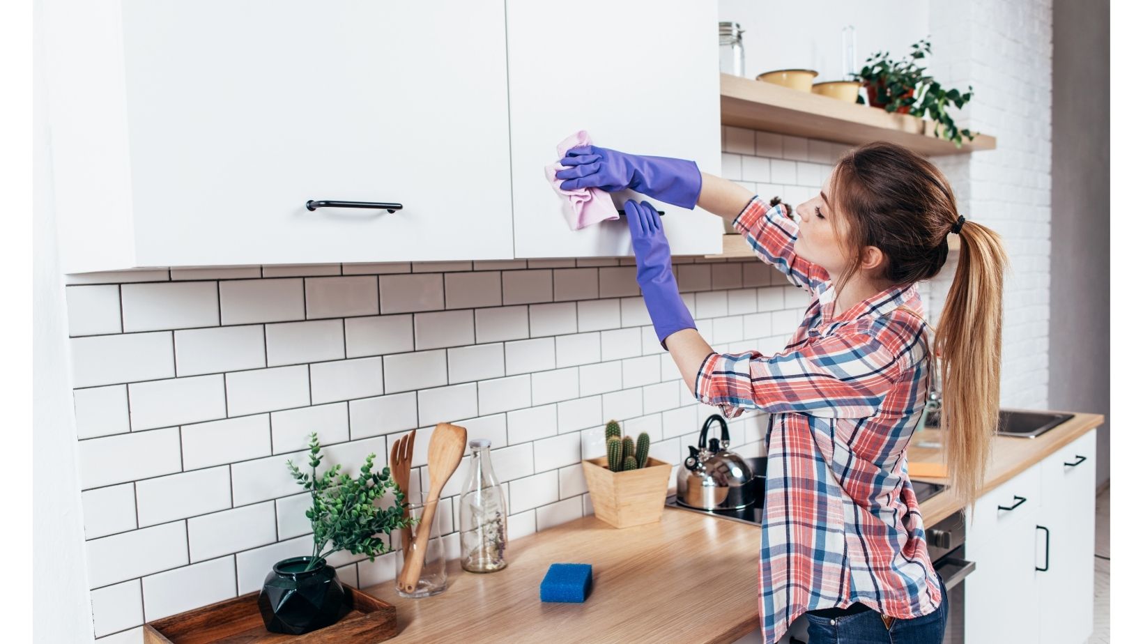 woman wearing rubber gloves wiping down kitchen cabinets