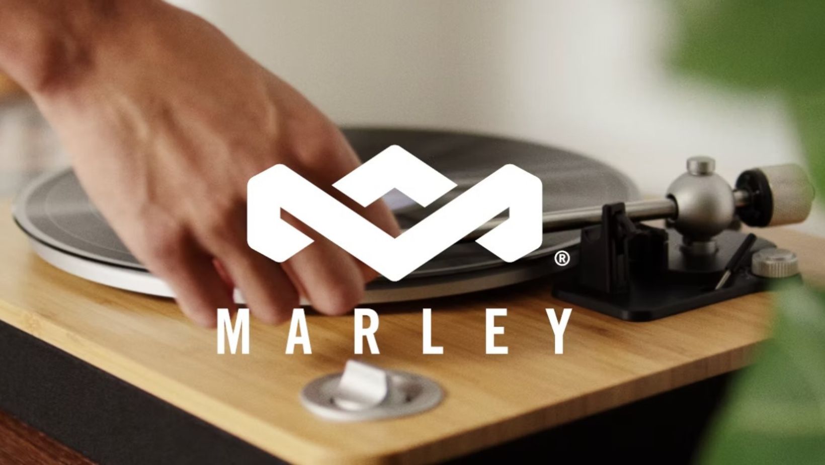 white house of marley logo over a photo of a hand placing a record on a record player