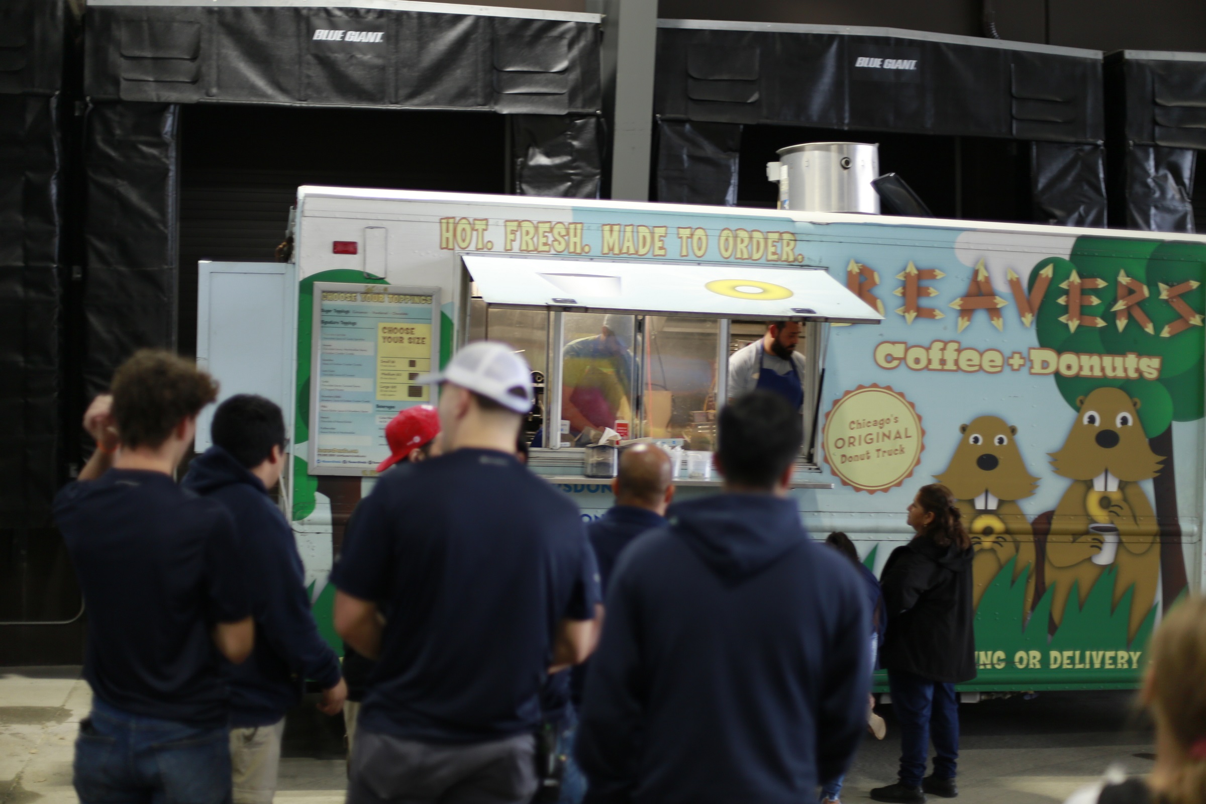 several people in navy shirts stand in front of a food truck with a beaver illustration to the right of the window