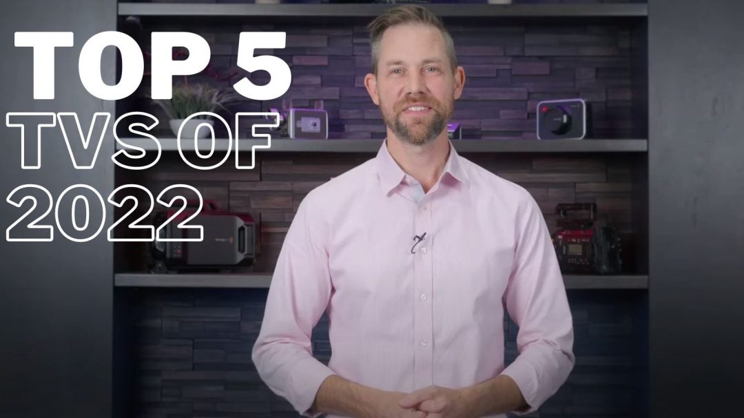 White text reads "top 5 TVs of 2022" on the left side of a man with a beard wearing a pale pink button down shirt