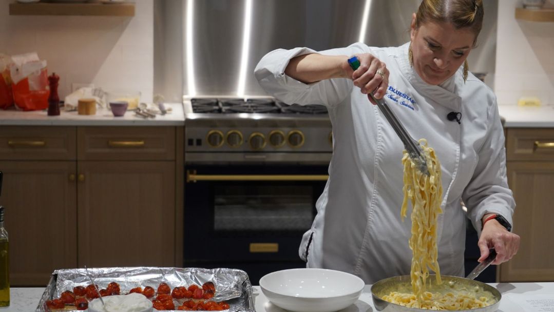 Chef Susan's pulling Fettuccine Alfredo noodles high
