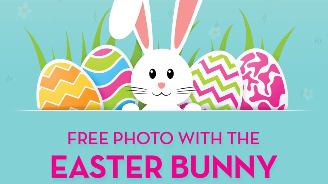 An image of a cartoonish bunny surrounded by colorful easter eggs. The text says "Free Photo With The Easter Bunny"