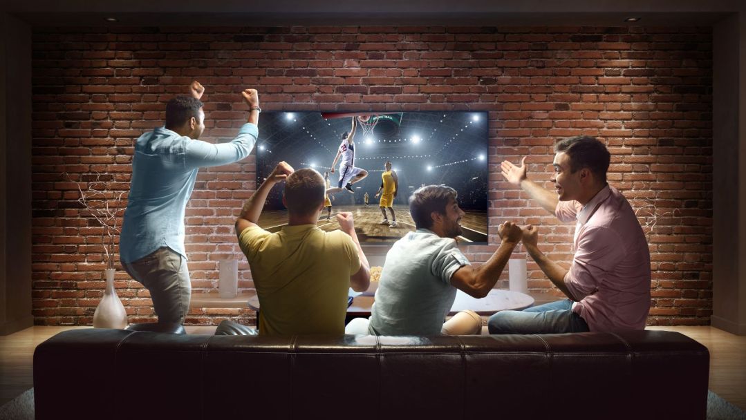 group of men on a leather couch cheering for a basketball game on TV
