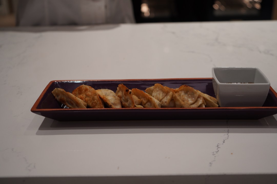 Potstickers and suace on a purple plate