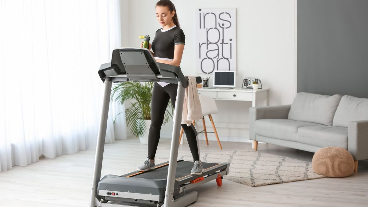 Young woman prepping for her training session on a treadmill indoors