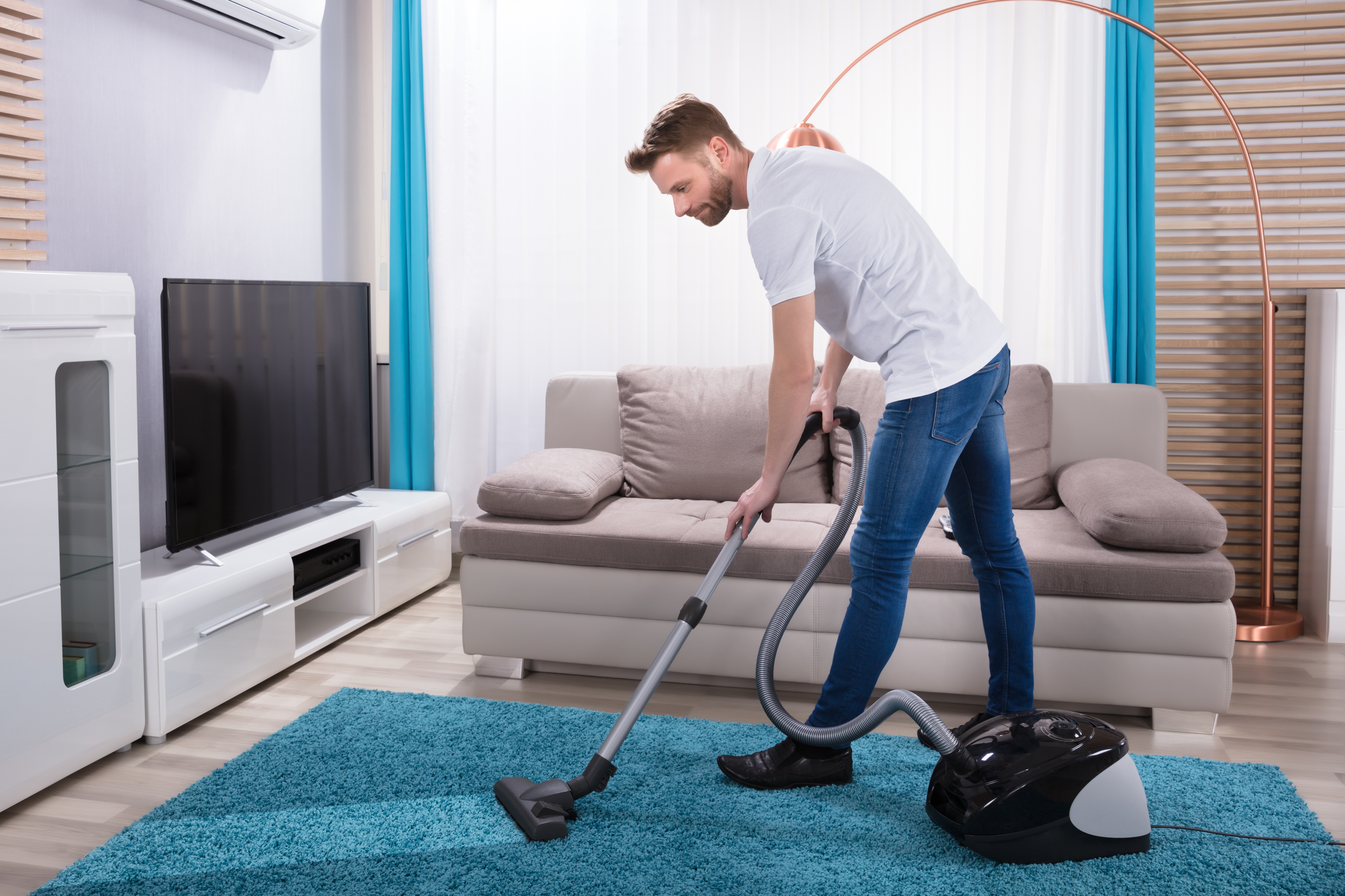 Man vacuuming rug in living room.