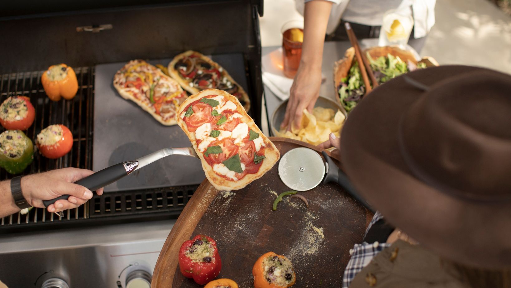 person lifting pizza off a Weber gas grill