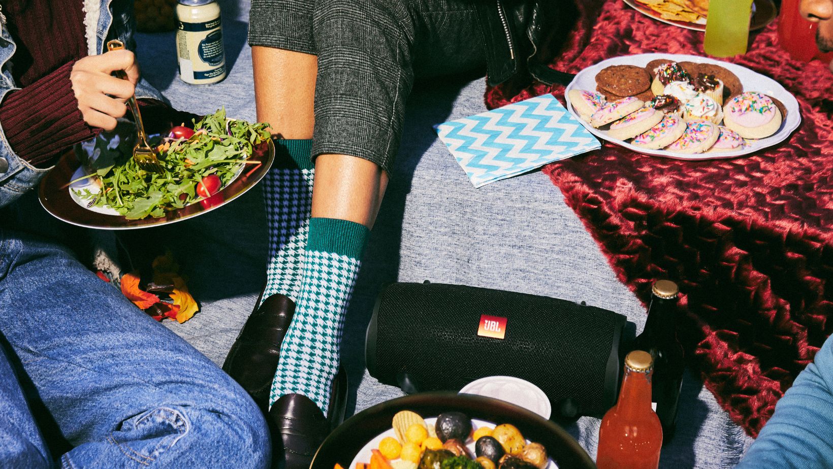 jbl speaker on picnic blanket with food and drinks