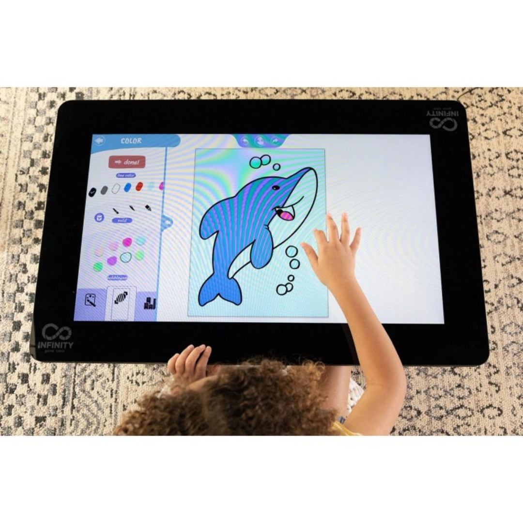 A small table with a full screen surface, a child is using the game table toy screen to color a picture of a dolphin.