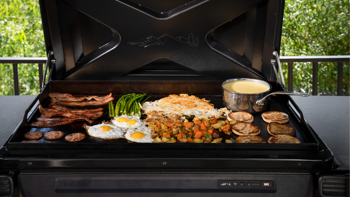 A flat top griddle cooking breakfast foods and heating a pot of creamy hollandaise