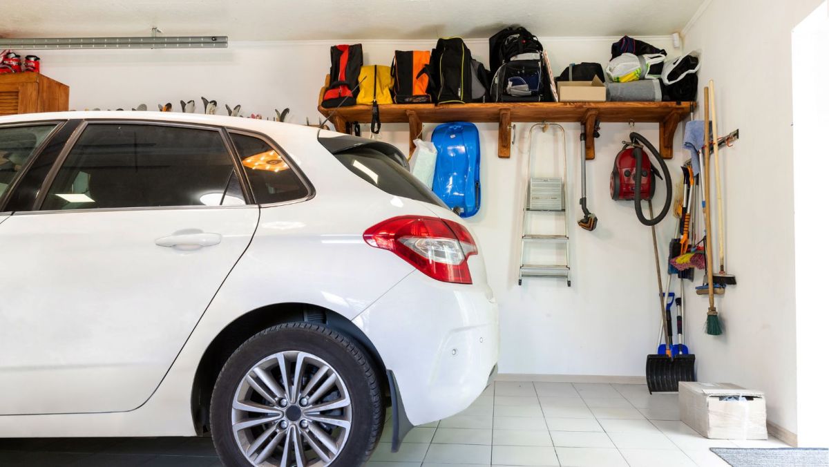 A parked car in an organized garage with wall storage for shovels, brooks, vacuums, bags and more.