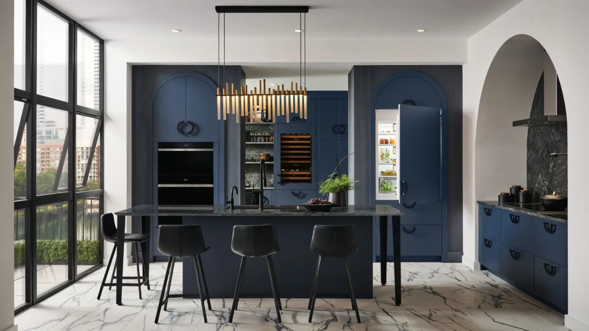 A beautiful city kitchen with all-blue cabinetry and appliances, unique lighting and striated floors.