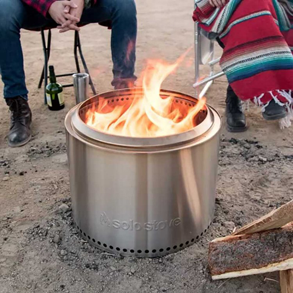 A silver portable fire pit lit in front of a group of people