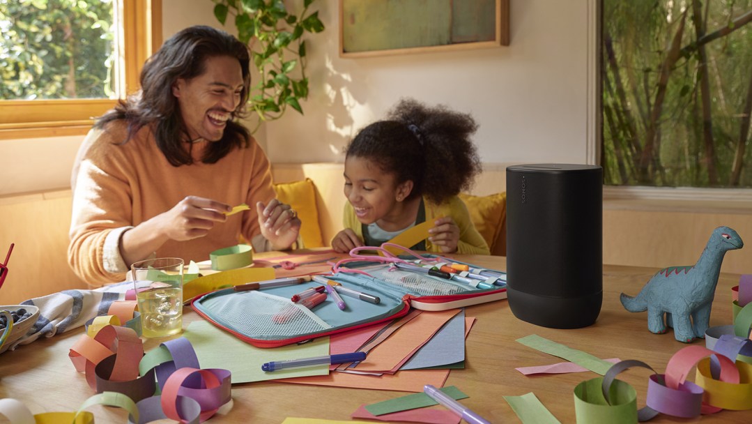A man and a little girl sitting at a table doing arts & crafts. The Sonos Move 2 speaker is next to them.