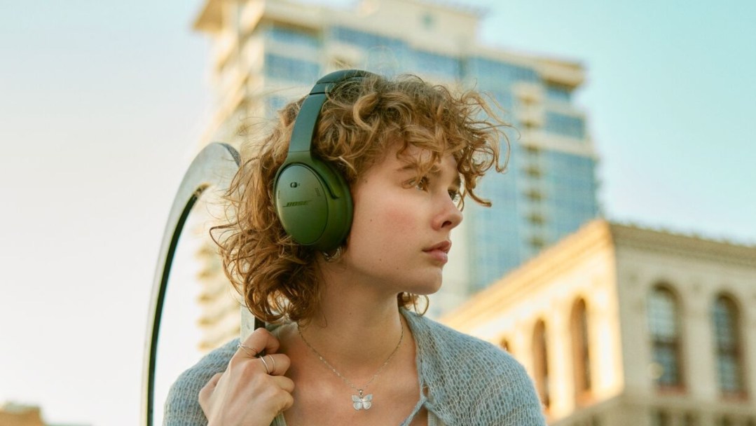 A woman walking outside wearing the Bose QuietComfort headphones