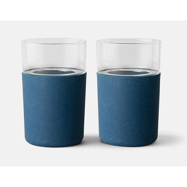 Two clear glasses with blue silicone sleeves on the bottoms.