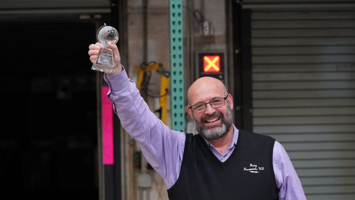 Gary smiling and holding up a crystal award shaped like a globe on a pedestal.