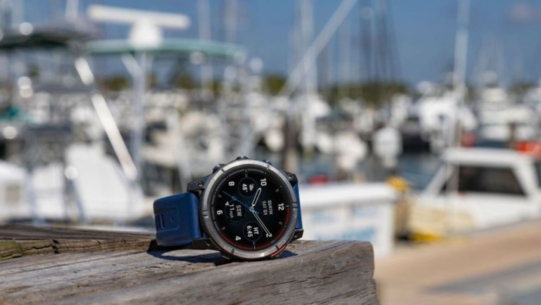 The Garmin quatix7 watch on a dock in front of out-of-focus boats