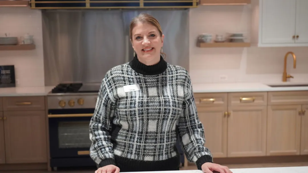 Susan Swanson smiles, leaning forward against the countertop in Abt's bluestar kitchen