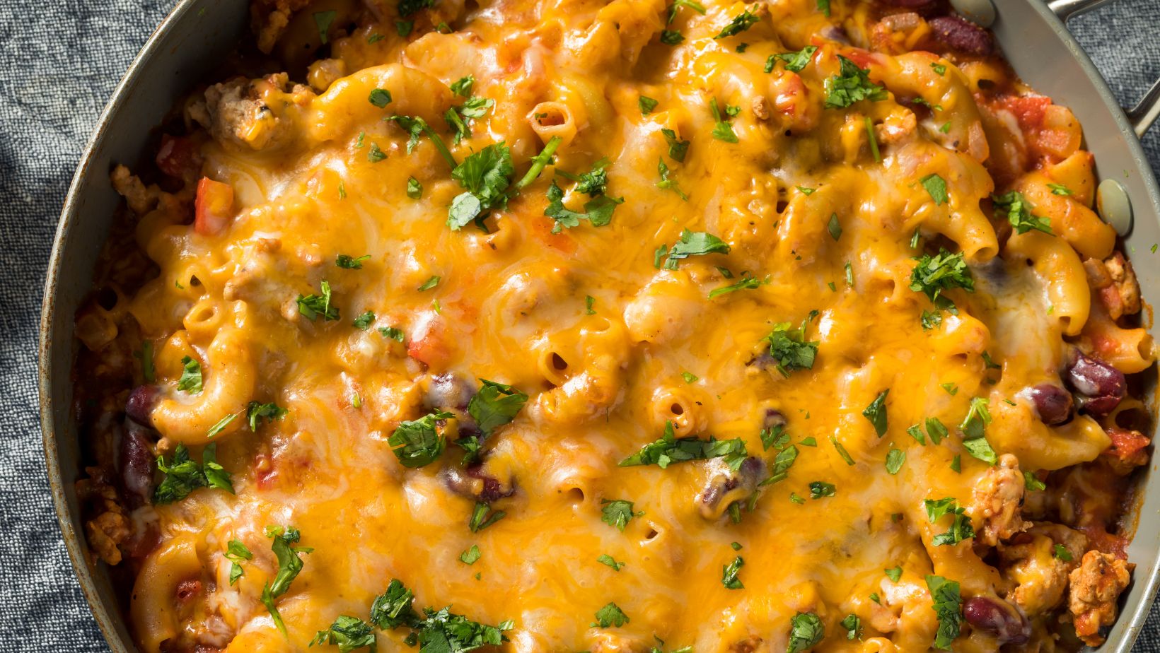 A zoomed in photo of a large pot of chili mac, topped with lots of cheese