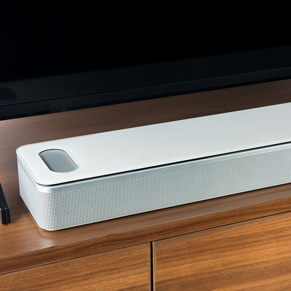 A close up of the white Bose Smart Ultra soundbar sitting on a TV stand