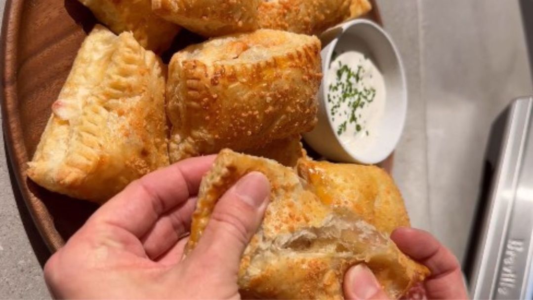 Pizza pockets being pulled apart with a bowl of ranch nearby for dipping on game day