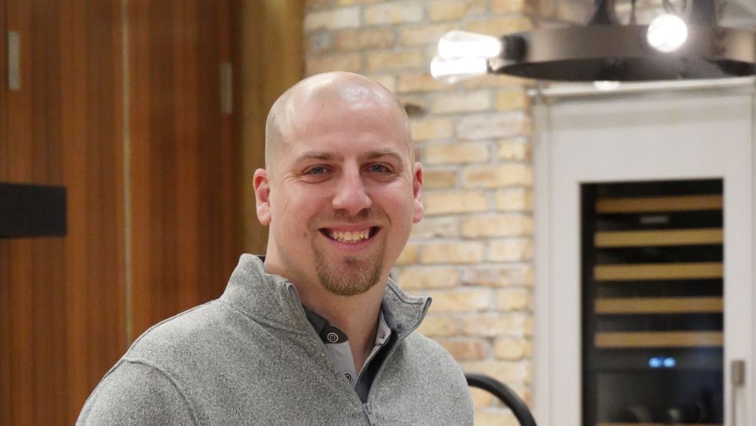 Rafal Kubalski in a gray quarter zip, smiling, in one of Abt's inspirational kitchens