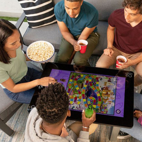 A group of friends in a game room playing Candyland on the Arcade1Up game table