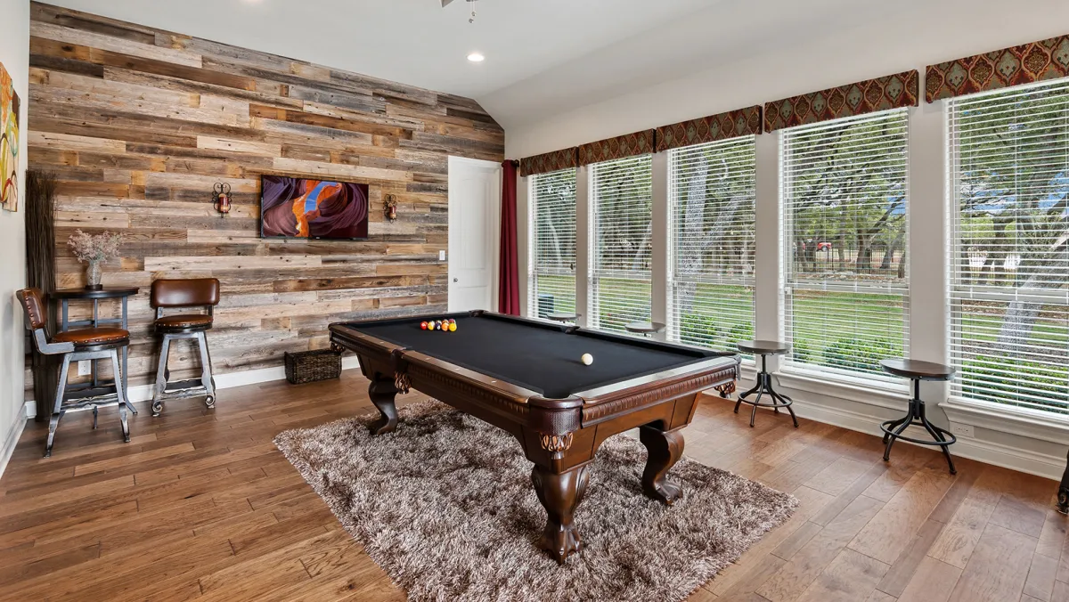 A pool table sitting on a rug in the middle of a hardwood room