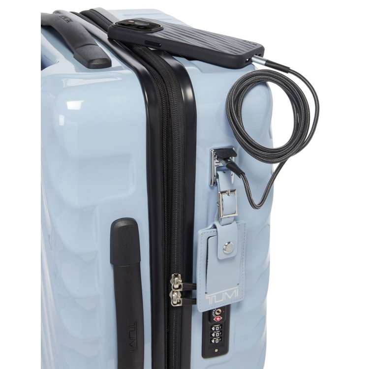 A zoomed in corner shot of the halogen blue TUMI 19 Degree Carry-On luggage. Focus is on the built-in charger as it charges a phone