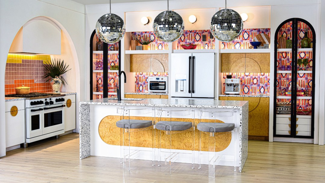 A shot of the Cafe KBIS 2024 booth, featuring a colorful kitchen with a countertop bar, patterned wallpaper and disco balls.