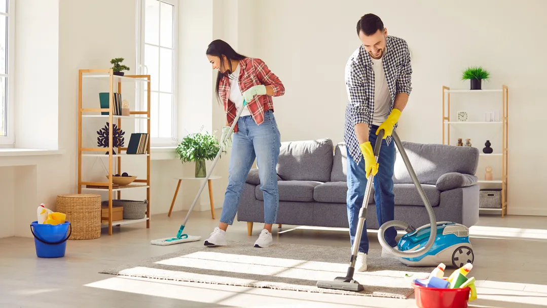A man and a woman doing spring cleaning chores in their living room