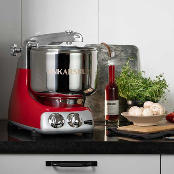 A red and silver stand mixer sitting on a countertop next to cooking ingredients.