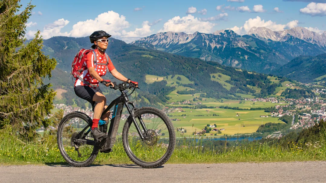 A women riding an electric bike in front of a mountain range