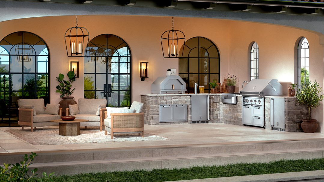 A covered stone patio with cushioned outdoor furniture, chic hanging lights and a luxury outdoor kitchen.